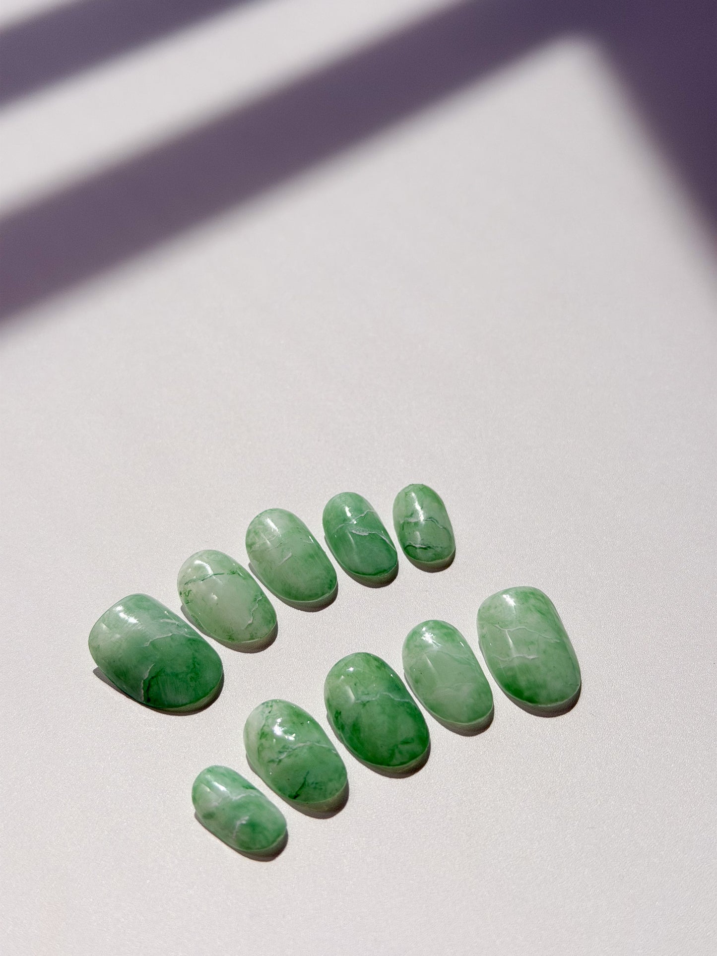 Green jade stones on a light surface with a soft shadow