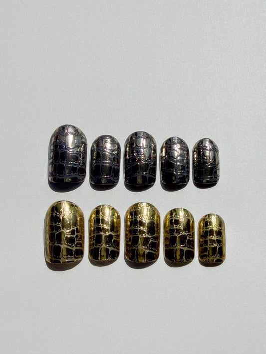 Set of gold and black crocodile patterned nail wraps on a gray background